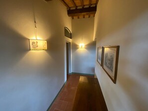 A hallway with a tiled floor, a wooden ceiling, and wall-mounted lighting fixtures. - Villa Stalletta Hot Tub by Geco Vacation Rentals (Bolgheri)