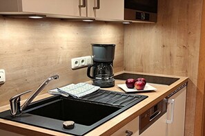 Eine Küche mit einem schwarzen Spülbecken, einer Kaffeemaschine und einem Geschirrgestell.