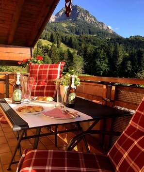 Ein Essbereich im Freien mit einem Tisch für zwei Personen, mit Blick auf eine gebirgige Landschaft.