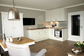A modern kitchen with white cabinetry, a wooden countertop, and a built-in oven. - Holiday apartment with 1 bedroom (Braunlage)