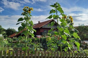 A house with a red roof and a garden with sunflowers. - Irlmühl "Spatzennest" (Schwarzach)