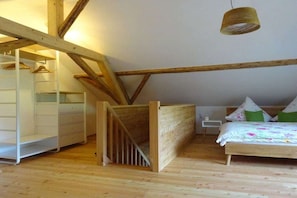 A bedroom with a wooden bunk bed, a bedside table, a hanging light fixture, and a wardrobe. - Irlmühl "Spatzennest" (Schwarzach)