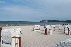 Strandliegen an einem sandigen Strand, im Hintergrund das Meer.