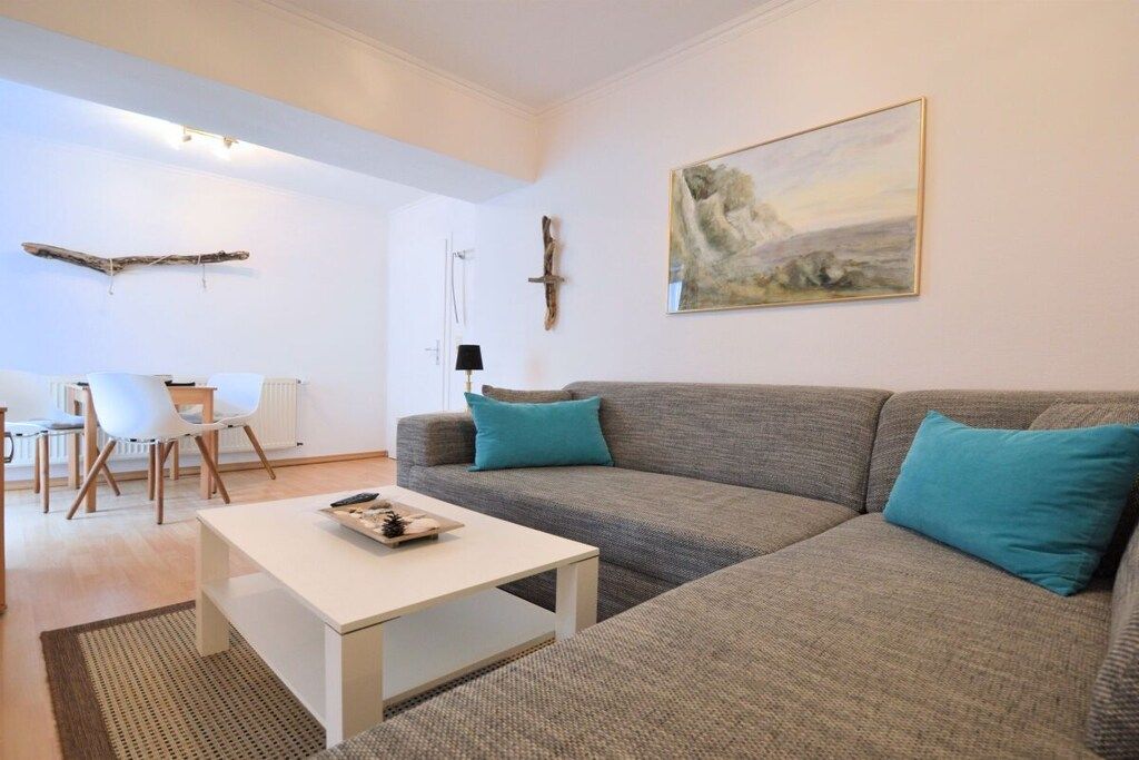 Una sala de estar moderna con un sofá gris, una mesa de centro blanca y un cuadro en la pared.