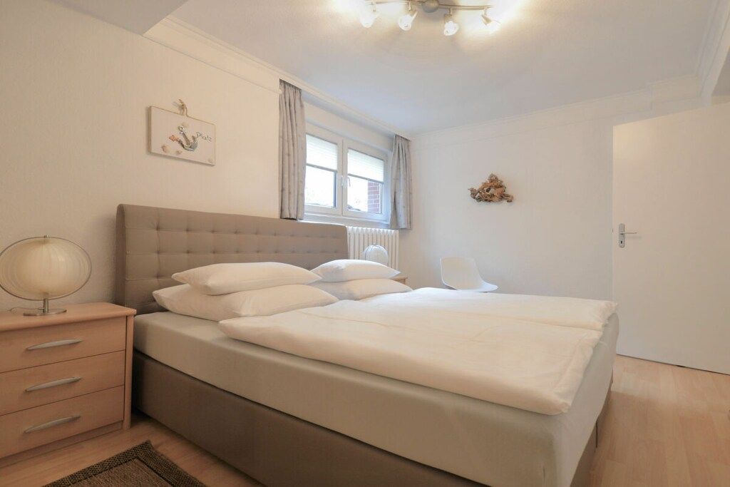 A bedroom with a bed, bedside table, lamp, and a window with curtains.