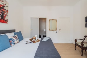 Habitación de hotel con cama, una silla, un espejo y un cuadro en la pared.