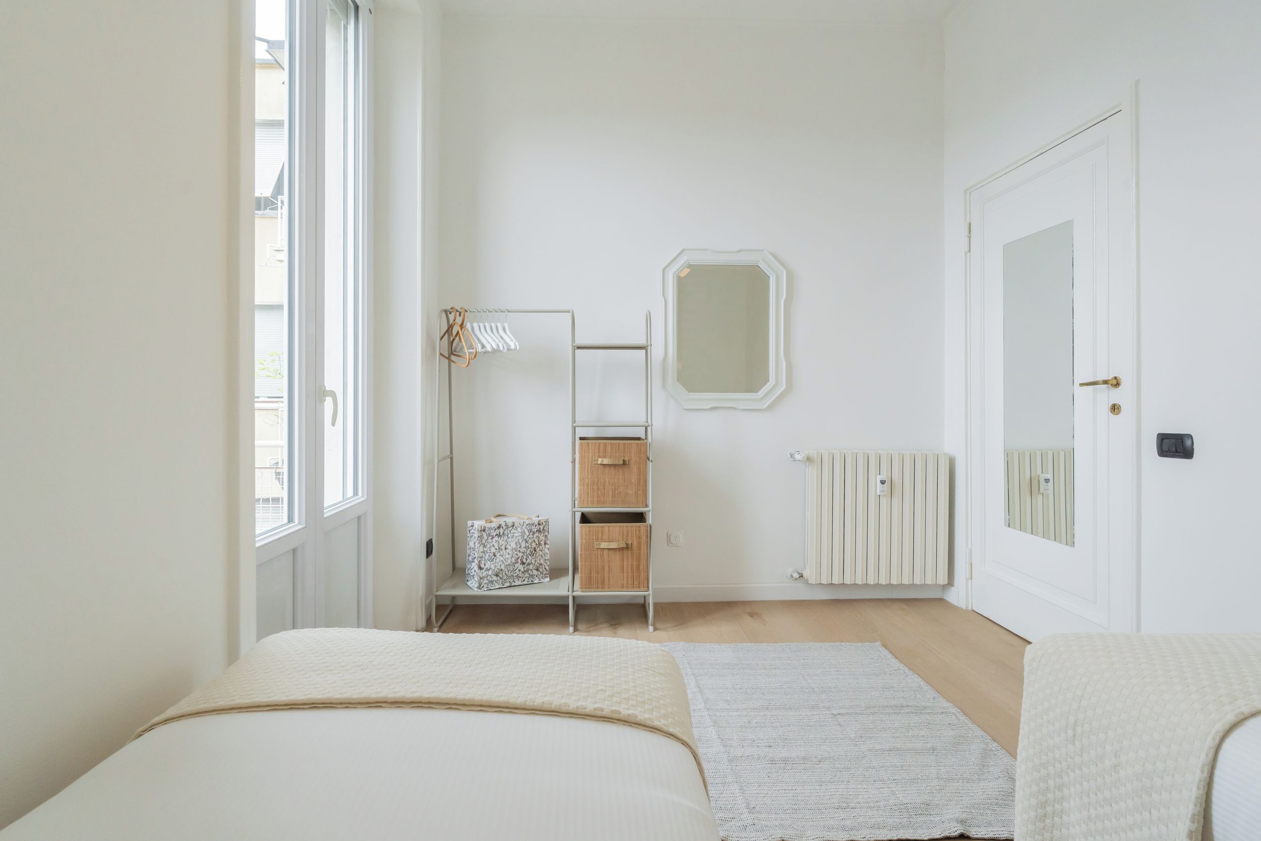 Ein Schlafzimmer mit Bett, Kleiderschrank, Heizkörper und Spiegel.
