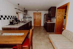 Une cuisine compacte comprenant une table à manger et un canapé, une porte en bois et un revêtement mural en carreaux.