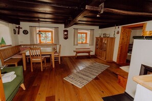 Une pièce chaleureuse avec un plancher en bois, un banc, une table et une cheminée.