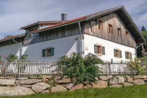 A two-story building with a white facade and wooden exterior. - Holiday home with 1 bedroom (Neuschönau)