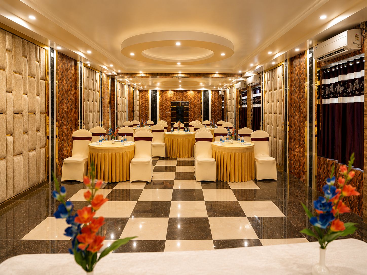 A hotel conference room with round tables, chairs, and a checkered floor.