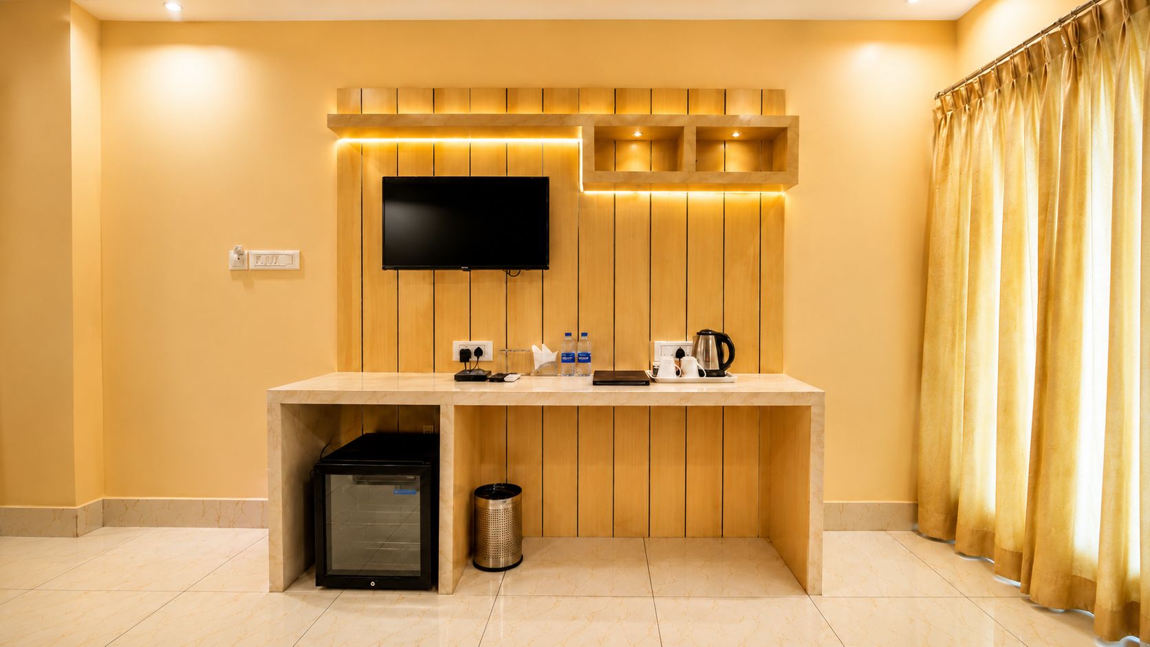 Une chambre d’hôtel avec un mur recouvert de panneaux de bois, un téléviseur à écran plat fixé au-dessus d’un comptoir et un petit réfrigérateur.
