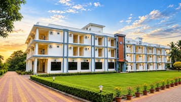 Un hotel de varios pisos con un patio central, unidades de aire acondicionado y un césped bien cuidado.