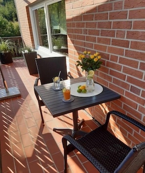 Eine Terrasse im Freien mit einem Tisch für zwei Personen, einem Stuhl und einem Blumentopf.