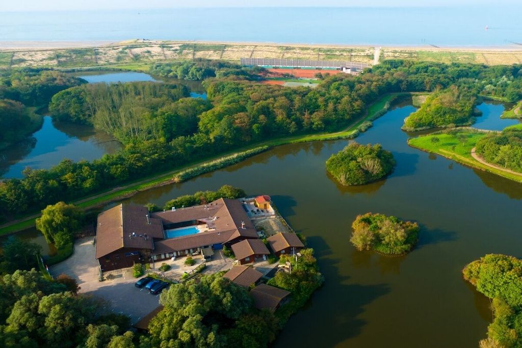 Luchtfoto van een pand met een zwembad, omringd door water en groen.