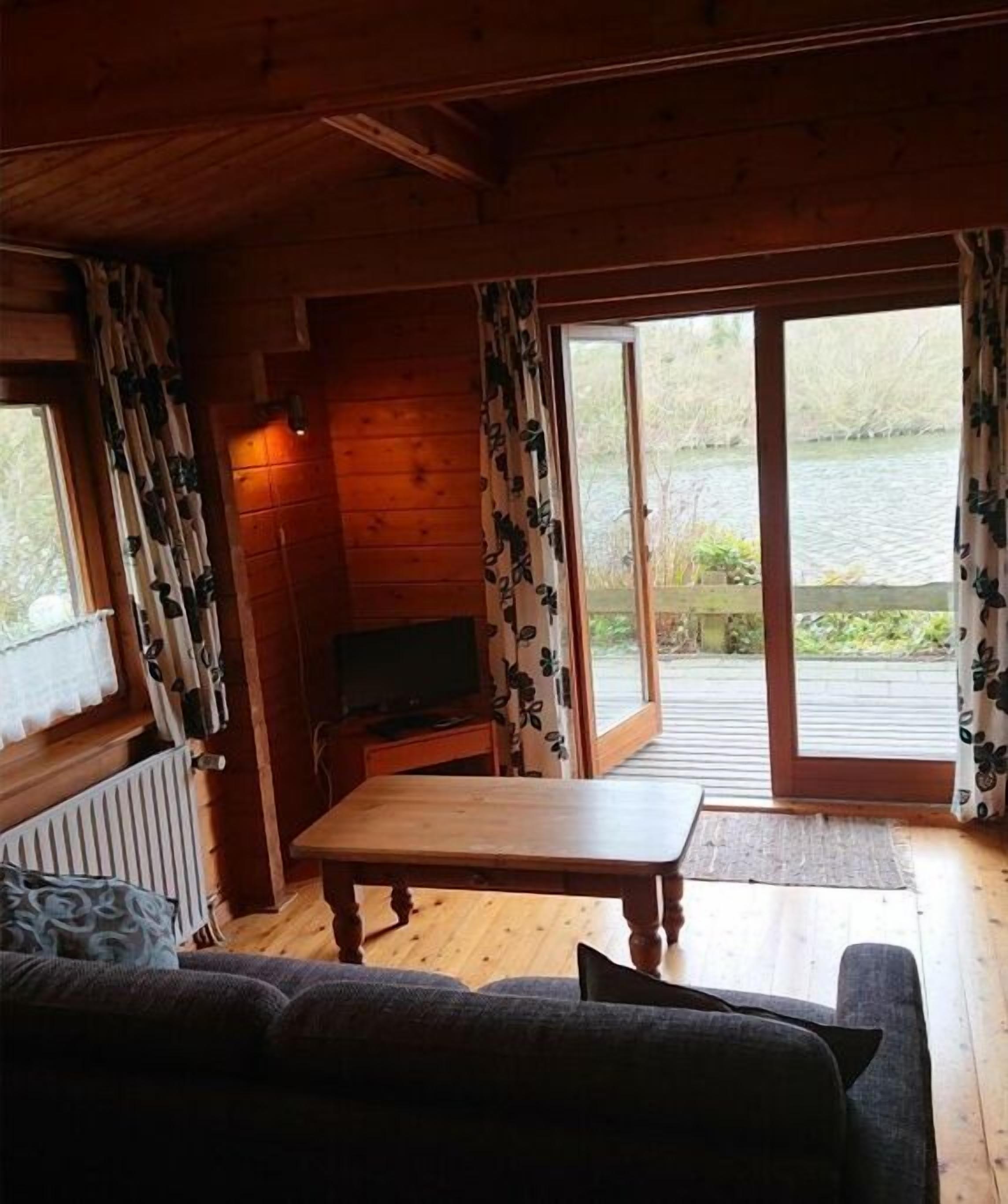 A cabin interior with a wooden table, sofa, and a television.