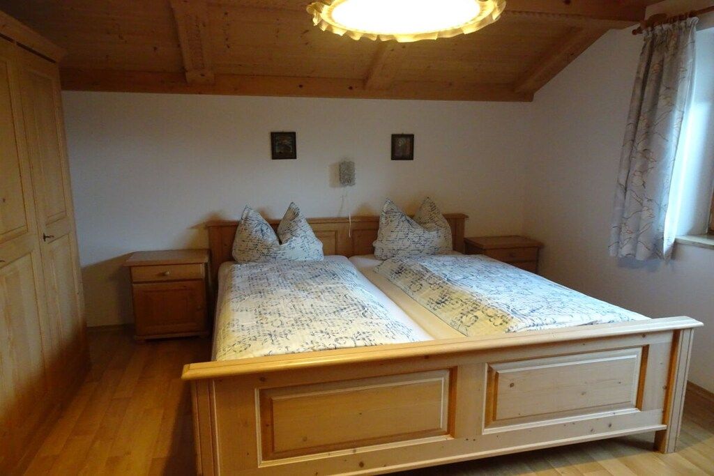 Una cama de madera con cabecera, dos mesitas de noche y una lámpara en el techo.