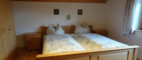 Una cama de madera con cabecera, dos mesitas de noche y una lámpara en el techo.