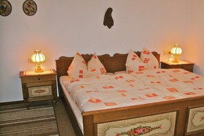 Una habitación de hotel con una cama de madera, dos mesitas de noche con lámparas, suelo cubierto de alfombra y decoración en las paredes.