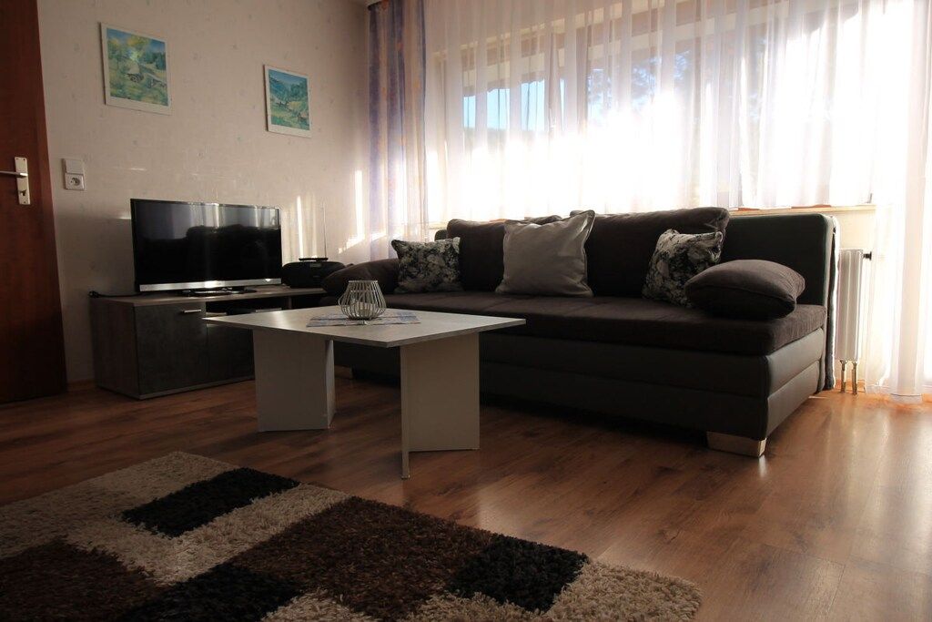 Un salon avec un canapé, une table basse, un téléviseur à écran plat et un tapis.