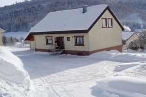 A two-story house with a snow-covered roof and a visible chimney. - Holiday apartment with 2 bedrooms (Baiersbronn-Obertal)
