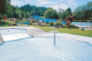 A swimming pool area with a hot tub, a slide, and a small waterfall feature. - Holiday apartment with 2 bedrooms (Baiersbronn-Obertal)