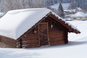 A wooden cabin with a snow-covered roof and a wooden door, surrounded by a snowy landscape. - Holiday apartment with 2 bedrooms (Baiersbronn-Obertal)