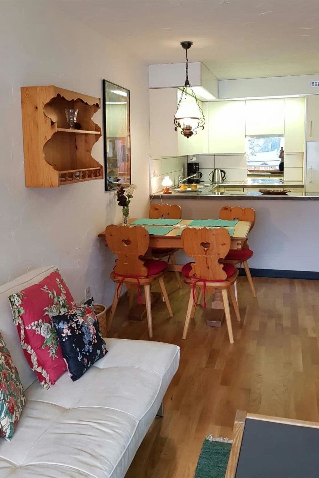 A compact living space with a dining area, kitchenette, and a sofa with floral cushions.