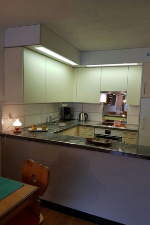 A compact kitchen with a built-in oven, a coffee maker, and a kettle on the counter. - Nevada 8 Appartement/Fewo, Dusche oder Bad, WC 1½-Zimmerwohnung by Interhome (Davos)