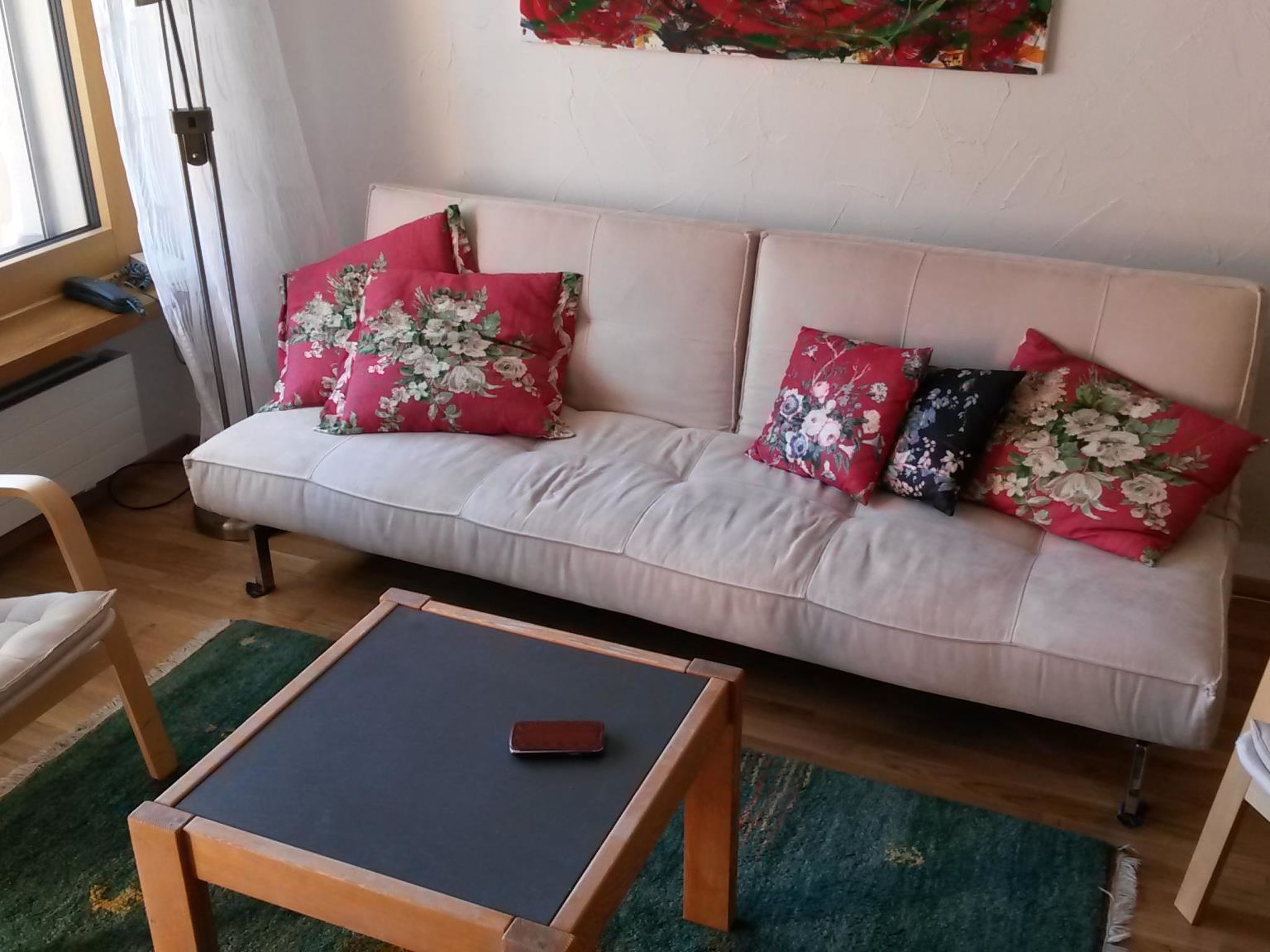 A living room with a sofa, a coffee table, and a painting on the wall.