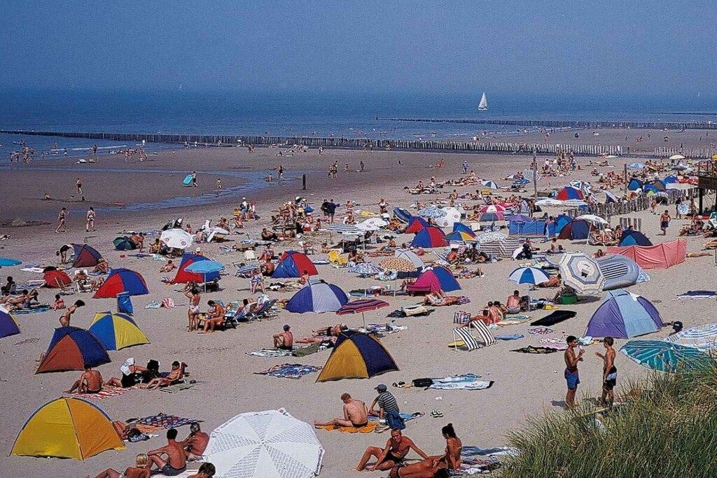 A crowded beach with numerous tents and umbrellas.