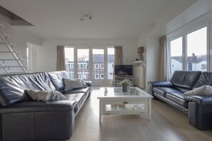 A modern living room with a sofa, a coffee table, and a TV. - Holiday apartment with 2 bedrooms (Cadzand-Bad)