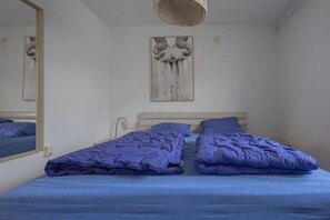 Une pièce avec un lit, un miroir et un tableau accroché au mur.