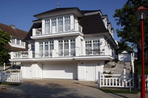 Ein zweistöckiges Wohnhaus mit Garage, Balkon mit Geländer und weißem Zaun.