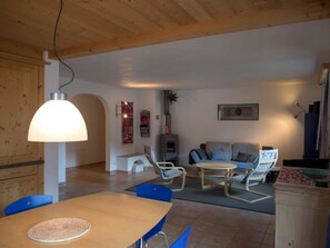 A spacious living area with a dining table, blue chairs, a sofa, and a ceiling lamp. - Heidblick Appartement/Fewo, Dusche oder Bad, WC 3½-Zimmerwohnung by Interhome (Klosters)
