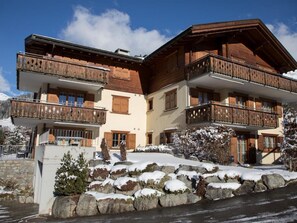 A multi-story building with wooden balconies, a stone facade, and a snow-covered landscape. - Heidblick Appartement/Fewo, Dusche oder Bad, WC 3½-Zimmerwohnung by Interhome (Klosters)