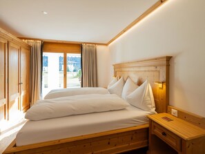 A bedroom with a wooden bed, a nightstand, and a window with curtains. - Valbella Park 102 Appartement/Fewo, Dusche oder Bad, WC 2 1/2-Zimmerwohnung by Interhome (Davos)