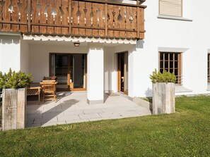 A building with a covered patio area, a wooden fence, and a small garden. - Valbella Park 102 Appartement/Fewo, Dusche oder Bad, WC 2 1/2-Zimmerwohnung by Interhome (Davos)