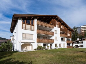 A multi-story building with wooden balconies, a white facade, and a grassy front yard. - Valbella Park 102 Appartement/Fewo, Dusche oder Bad, WC 2 1/2-Zimmerwohnung by Interhome (Davos)