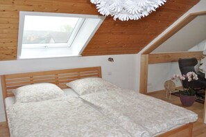 A bedroom with a wooden ceiling, a skylight, a bed with patterned bedding, and a potted plant. - Charming holiday apartment 3 (Salem)