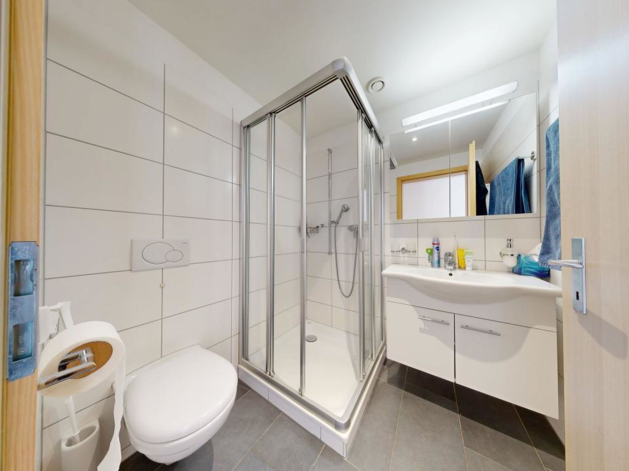 A modern bathroom with a glass-enclosed shower, a white toilet, and a vanity with a mirror.