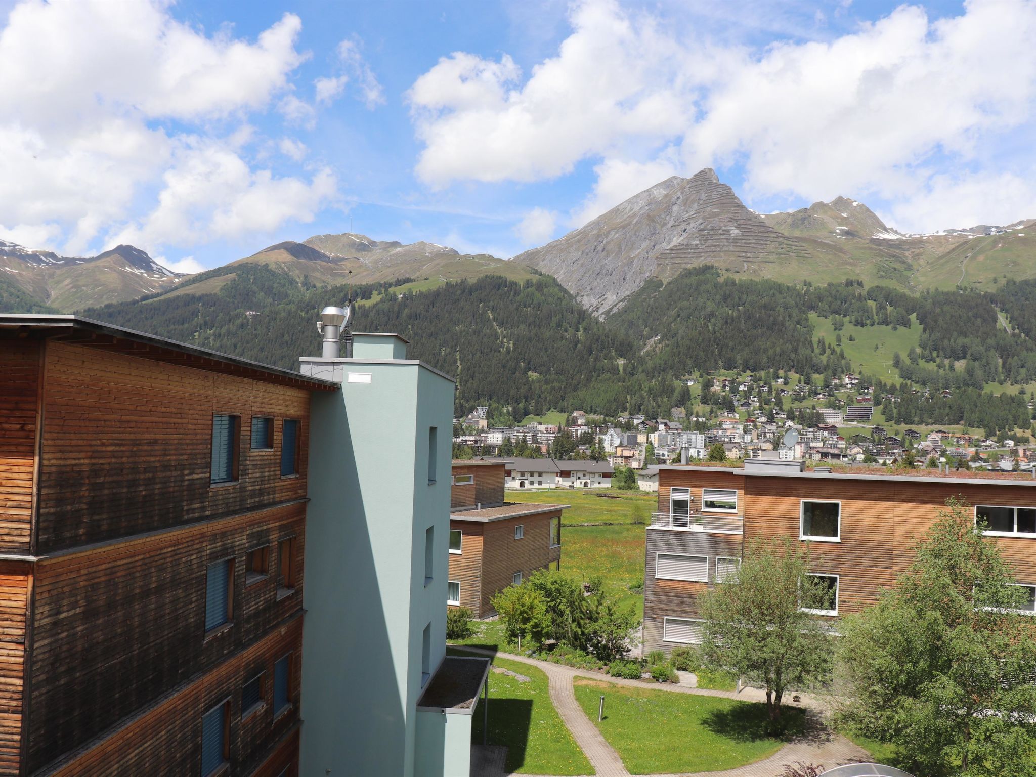 Zona residencial con edificios modernos, cielo despejado y montañas al fondo.