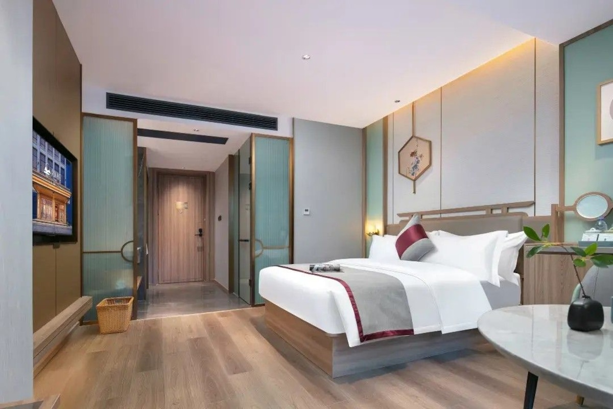 A modern hotel room with a bed, bedside table, and a television.