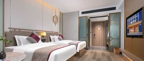 A hotel room with a bed, bedside tables, a wall-mounted TV, and a door leading to a bathroom.