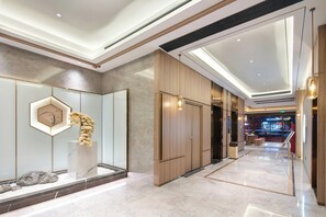 Un moderno vestíbulo de hotel con piso de mármol, una recepción y una decoración con plantas.