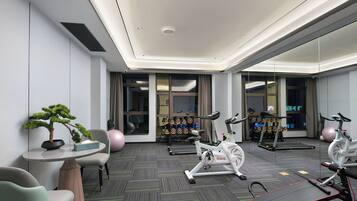 Un gimnasio moderno con equipo de ejercicio, un espejo y una planta en maceta.
