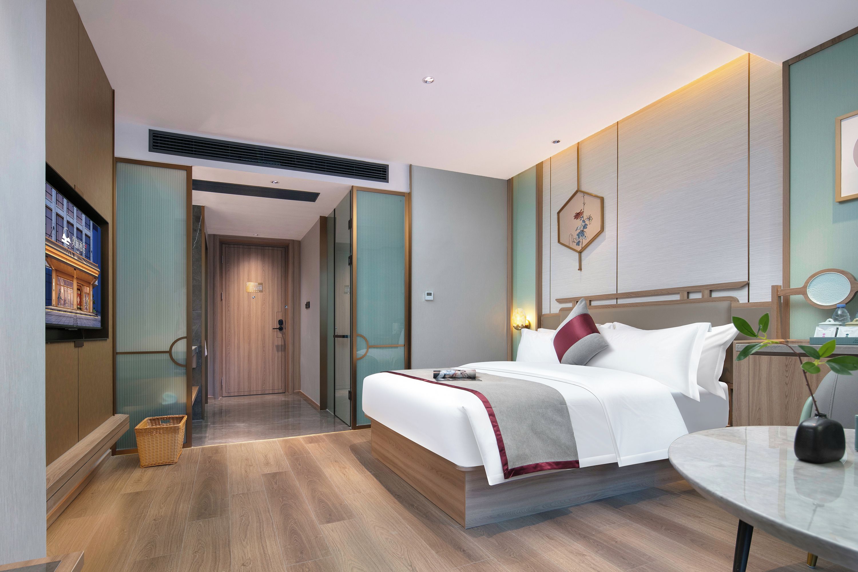 Quarto de hotel moderno com cama, mesa de cabeceira e televisão presa na parede.