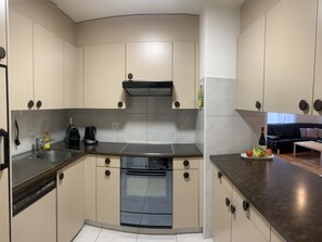 Een kleine keuken met een ingebouwde oven, een koffiezetapparaat en een spoelbak.