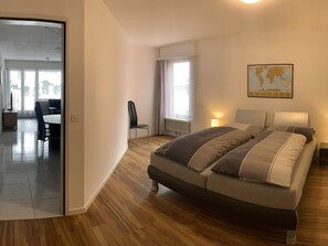 Een moderne slaapkamer met een groot bed, een bureau en een stoel.