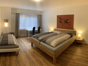 A bedroom with a double bed, a bedside table, a chair, a desk, and a window with curtains. - Quellenhof C01 Appartement/Fewo, Dusche oder Bad, WC 3½-Zimmerwohnung by Interhome (Davos)